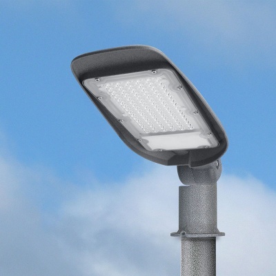 Candeeiro LED de iluminação pública cinza montado em poste com céu azul ao fundo