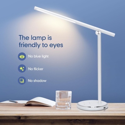 Candeeiro de mesa branco moderno com luz LED sobre mesa de madeira com copo de água e livro aberto