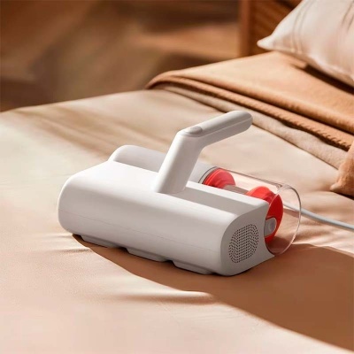 Aspirador portátil branco com detalhe vermelho sobre sofá ou cama bege
