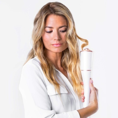 Vareta de modelar cabelo branca e dourada com cabelo loiro ondulado enrolado, segurada por mulher com camisa branca