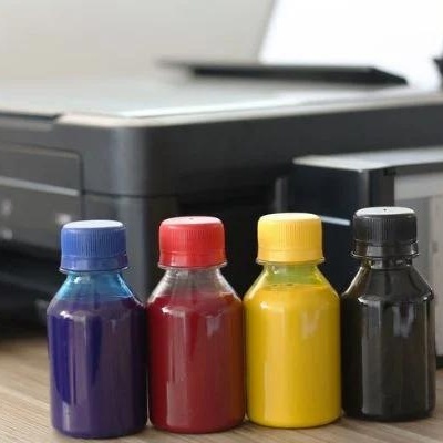 Impressora preta com quatro frascos de tinta coloridos à frente