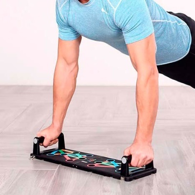 Aparelho de exercício de braço preto com desenhos coloridos e pegas pretas em chão cinzento claro