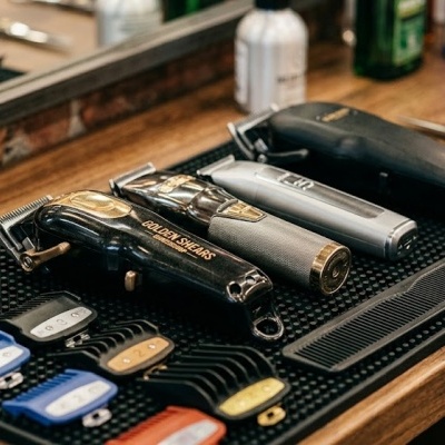 Máquinas de cortar cabelo, óleo, pente e tesouras em bancada de barbearia