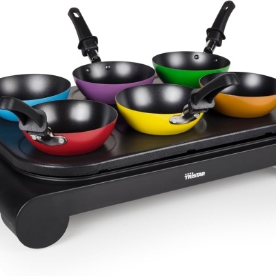 Conjunto de mini frigideiras coloridas sobre placa aquecedora elétrica preta