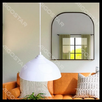 Candeeiro pendente branco sobre sofá laranja com almofadas e espelho na parede