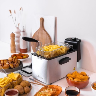 Fritadeira elétrica Tristar com batatas fritas e diversos petiscos em pratos na bancada