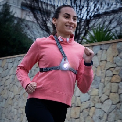 Mulher a correr com colete refletor cinzento com luz LED e sweatshirt rosa