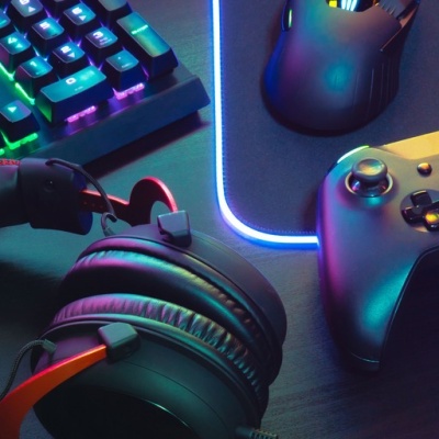 Auscultadores, teclado, rato e comando de jogo em mesa escura