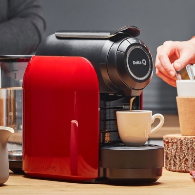 Máquina de café Delta Q vermelha a preparar café numa chávena branca