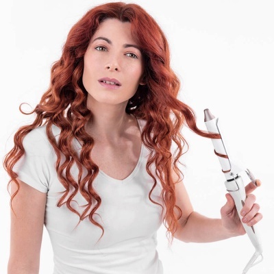 Mulher a usar modelador de cachos branco no cabelo vermelho