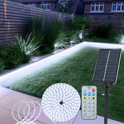 Fita LED branca com painel solar e comando à distância junto a piscina iluminada e jardim