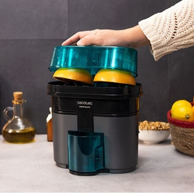 Espremedor de citrinos elétrico com duas metades de laranja em cima, bancada de cozinha cinza