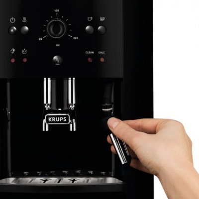 Máquina de café expresso preta com detalhes metálicos e mão ajustando alavanca