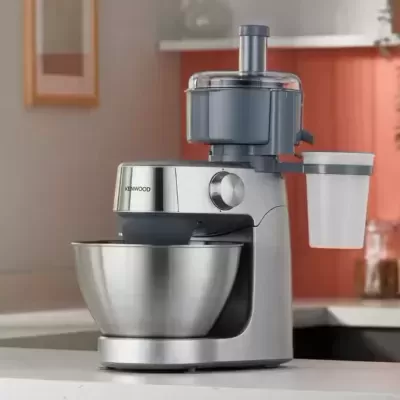 Máquina de cozinha Kenwood metálica e cinzenta numa bancada branca
