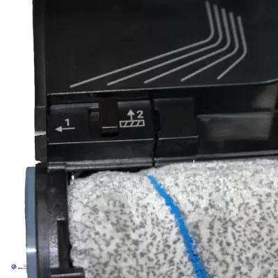 Máquina de limpeza com rolo de tecido cinzento e símbolos brancos num fundo preto