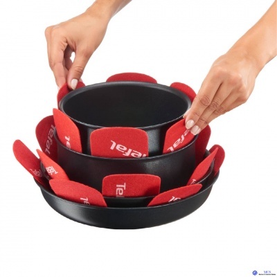 Recipientes de cozinha pretos com protetores vermelhos com a palavra Tefal nas bordas, segurados por duas mãos.