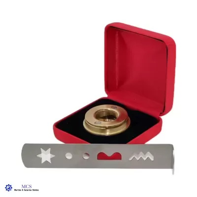 Objeto redondo dourado numa caixa vermelha aberta com barra metálica cinzenta com recortes distintos