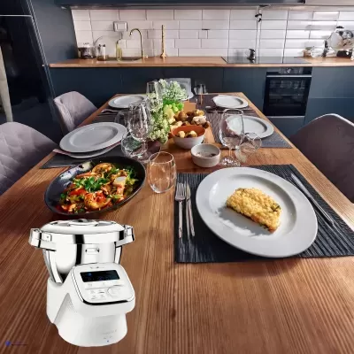 Mesa posta com pratos brancos e comida, máquina de cozinha branca, cozinha moderna ao fundo