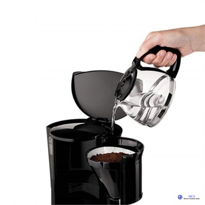 Máquina de café preta com jarro de vidro e mão a verter água