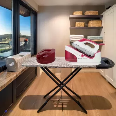 Prancha de engomar branca e rosa numa tábua de engomar cinza num quarto com janela grande