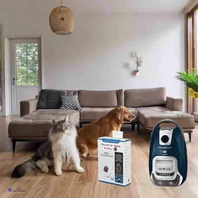 aspirador de pó azul escuro com branco ao lado da embalagem numa sala de estar com gato e cão