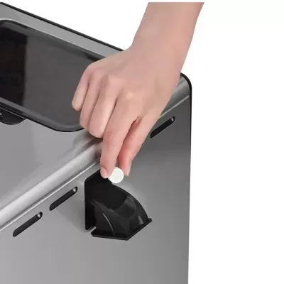 Mão segurando comprimido branco junto a dispensador metálico prateado