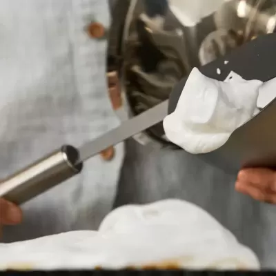 Espátula a aplicar creme branco espesso num recipiente preto