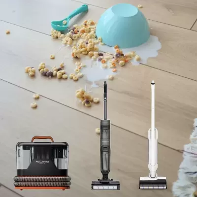 Chão de madeira clara com cereais e leite derramados, três aspiradores verticais abaixo