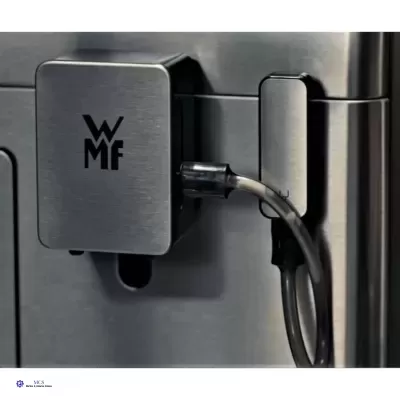 Produto metálico quadrado com logótipo 'WMF' e cabo preto numa superfície metálica