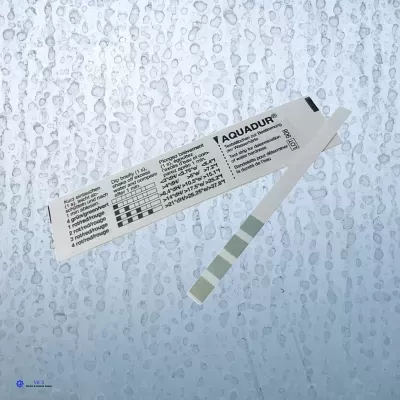 Tira teste Aquadur para dureza da água com cartão de instruções e gotas de água ao fundo