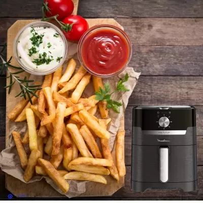 Batatas fritas com molhos e tomate numa tábua juntamente com fritadeira elétrica preta