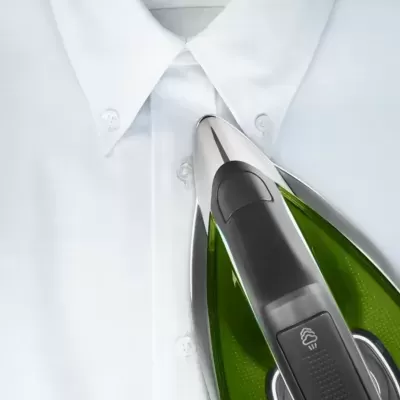 Ferro de engomar verde e prata numa camisa branca