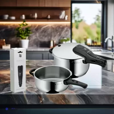 Conjunto de panelas de pressão em aço inox com cabos pretos e embalagem WMF PERFECT numa bancada de cozinha moderna