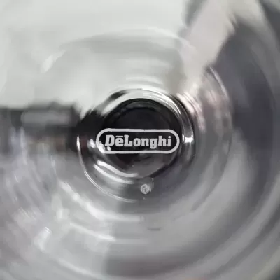 logótipo DeLonghi em objeto circular preto com reflexos metálicos