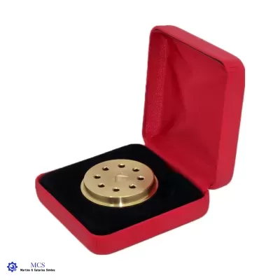Caixa vermelha aberta com objeto redondo dourado e almofada preta.
