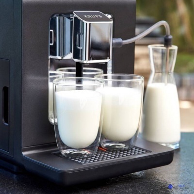 Máquina de café expresso preta com copos de vidro duplo com leite e jarra de vidro com leite