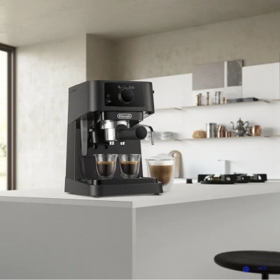 Máquina de café espresso preta com chávenas de vidro em bancada branca