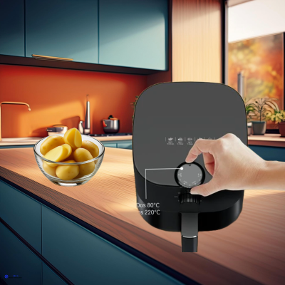 Fritadeira preta com regulador giratório numa cozinha com armários azuis e taça de vidro com batatas.