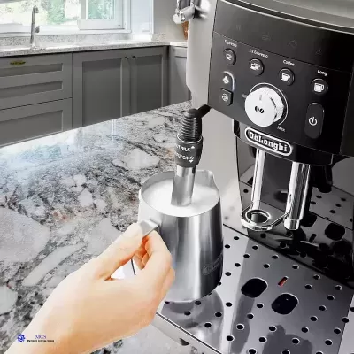 Máquina de café expresso DeLonghi com jarro de metal sobre bancada de pedra