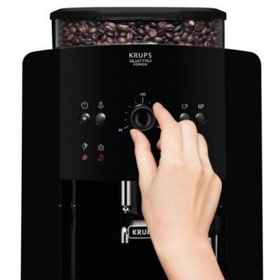 Máquina de café KRUPS Quattro FORCE preta com depósito transparente cheio de grãos e painel frontal com botões, mão ajusta botão de seleção.