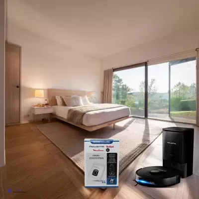 Quarto moderno com cama branca, chão de madeira e aspirador robô preto com caixa branca.