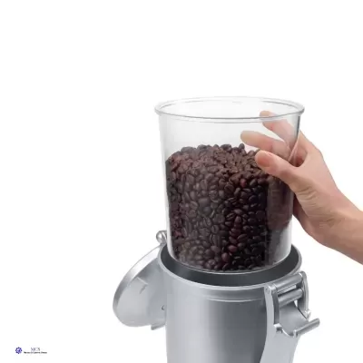 Recipiente transparente com grãos de café sendo colocado em moedor de café metálico.