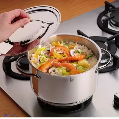 Panela de aço inoxidável com arroz, camarões e legumes no fogão