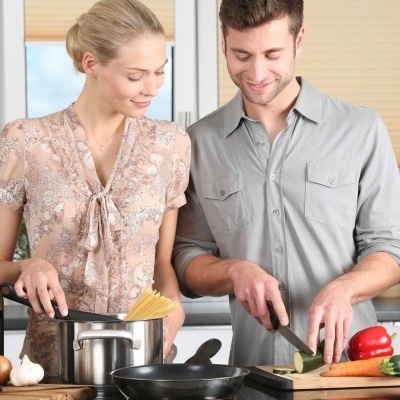 Casal a cozinhar na cozinha com legumes e macarrão