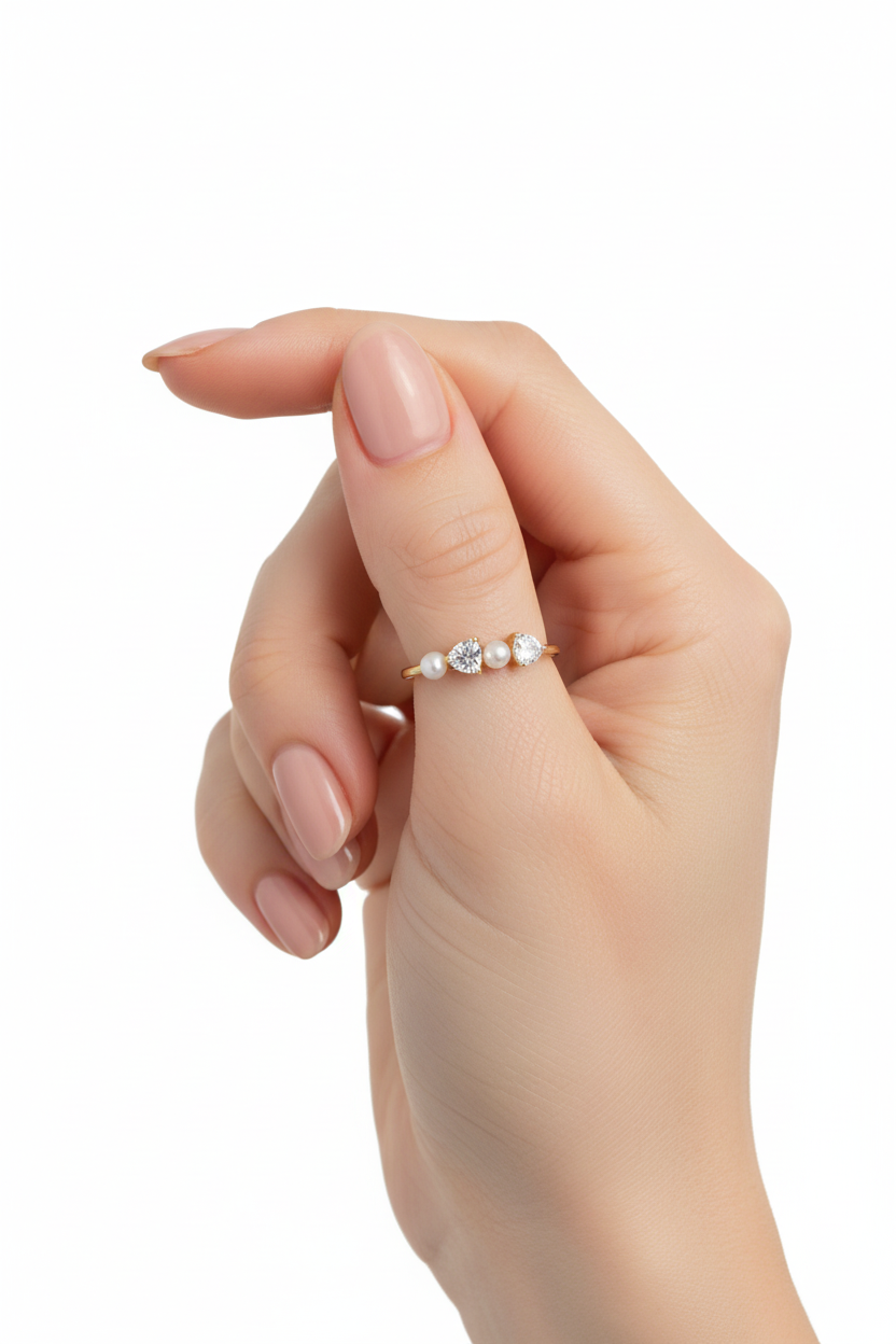 Anel dourado com pérolas e pedras em dedo feminino com verniz cor de pele