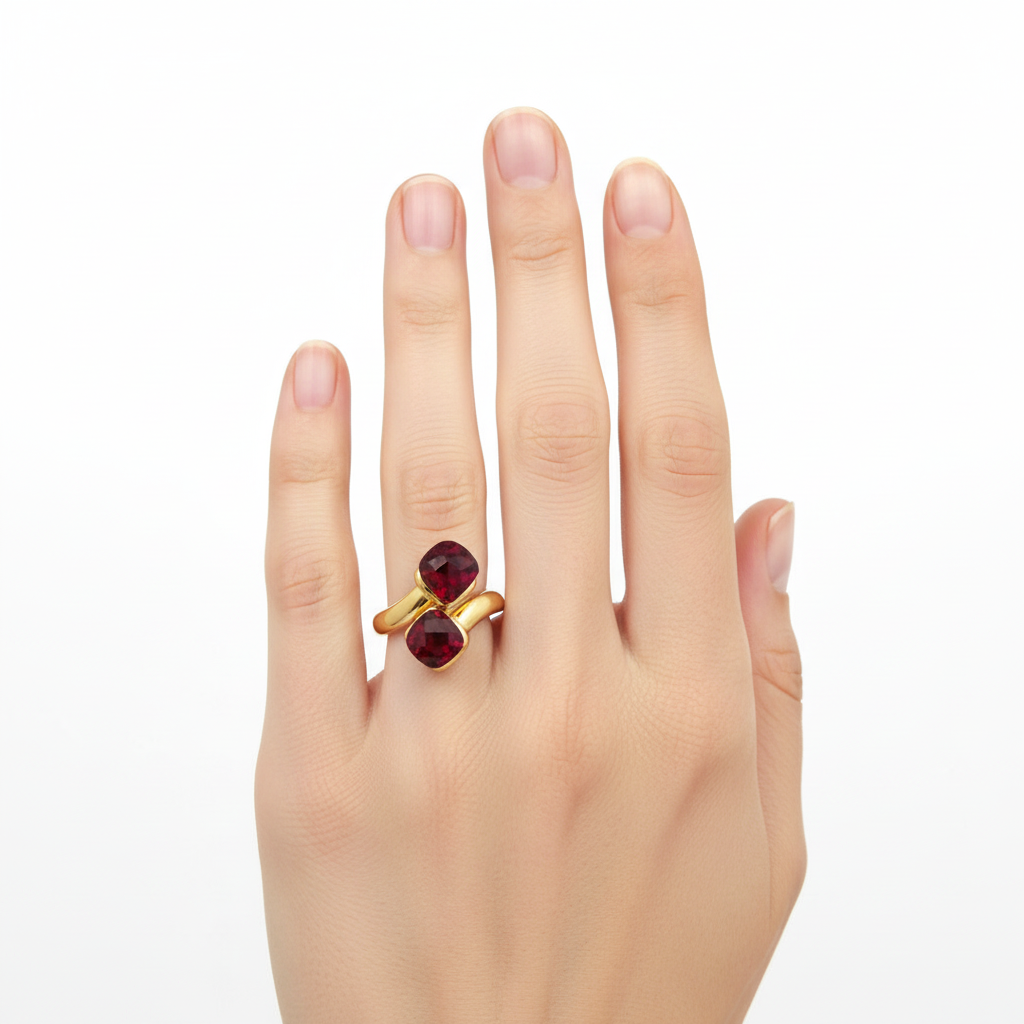 Mão feminina com anel dourado com pedras vermelhas.