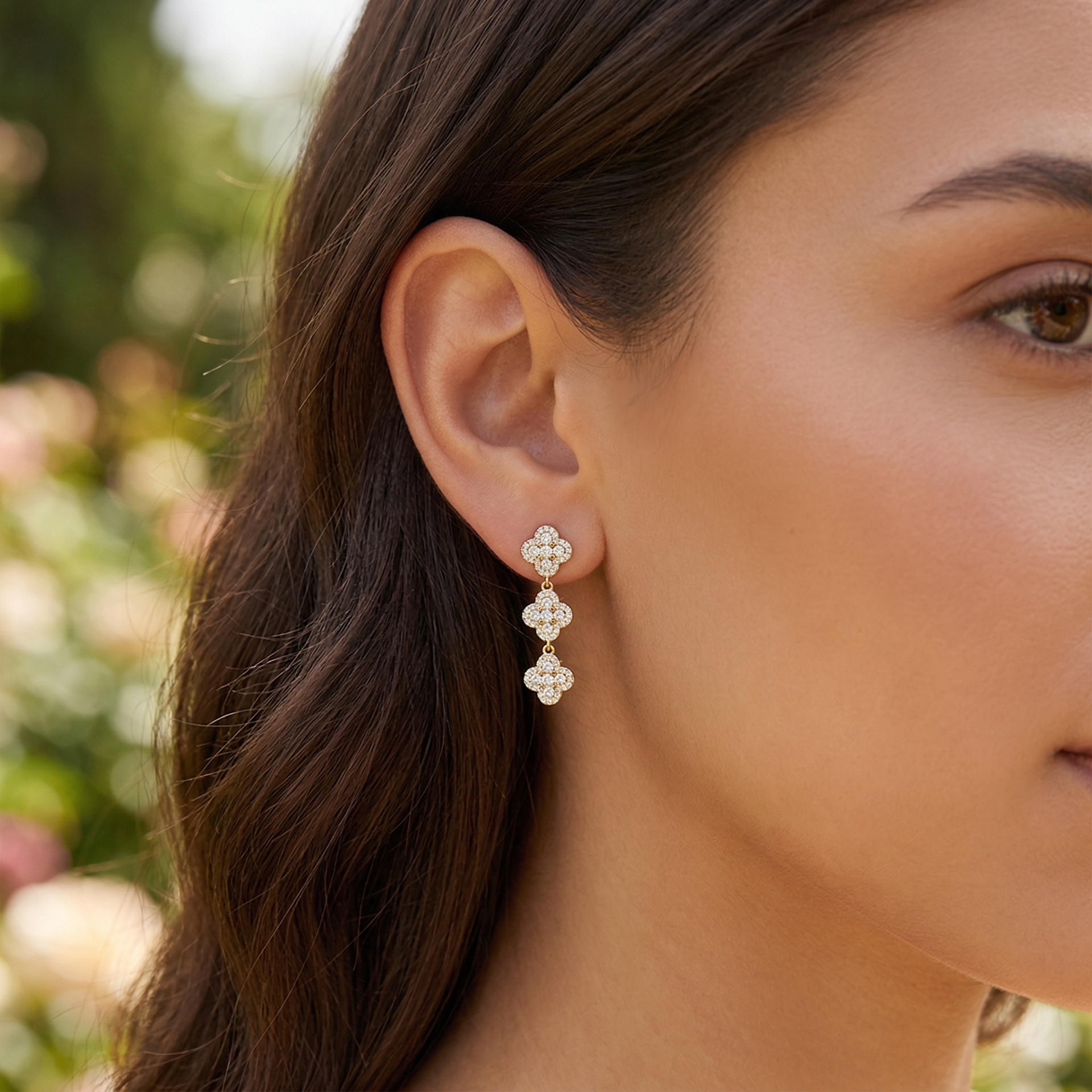Brincos pendentes dourados com pequenas pedras brilhantes em formato de trevo.