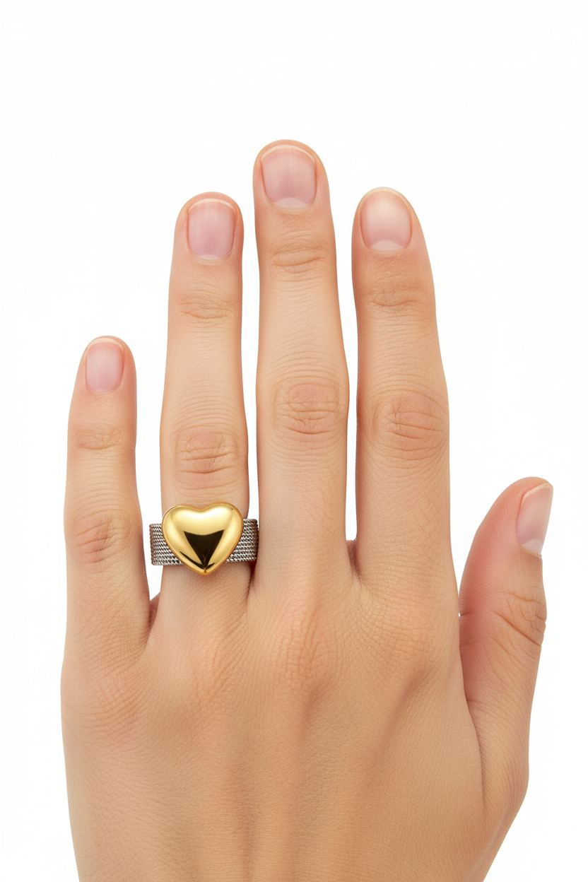 Anel de malha prateada com coração dourado polido em dedo anelar de mão feminina