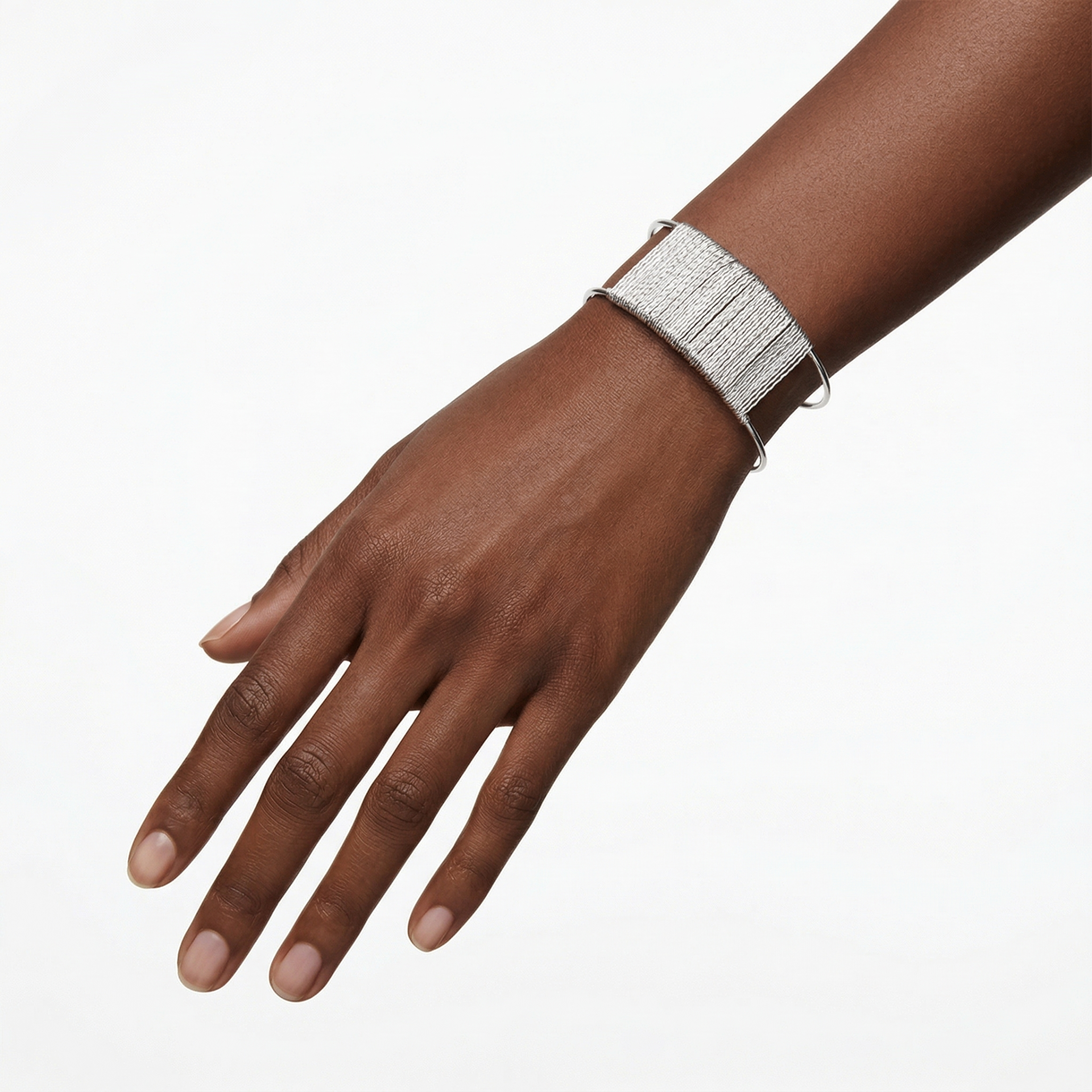 Pulseira prateada sobre pulso de mão com pele escura num fundo branco