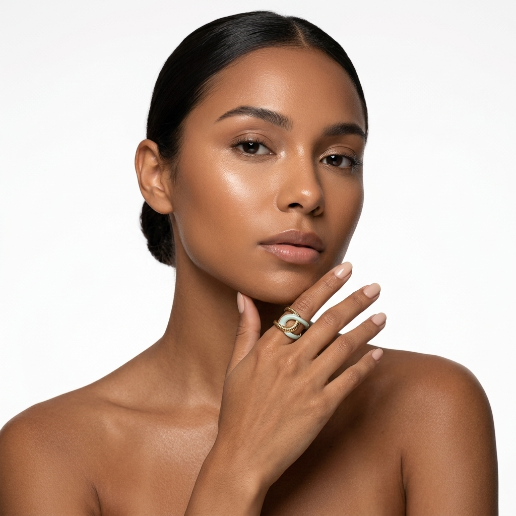 Mulher morena com anel dourado e verde claro na mão junto ao rosto